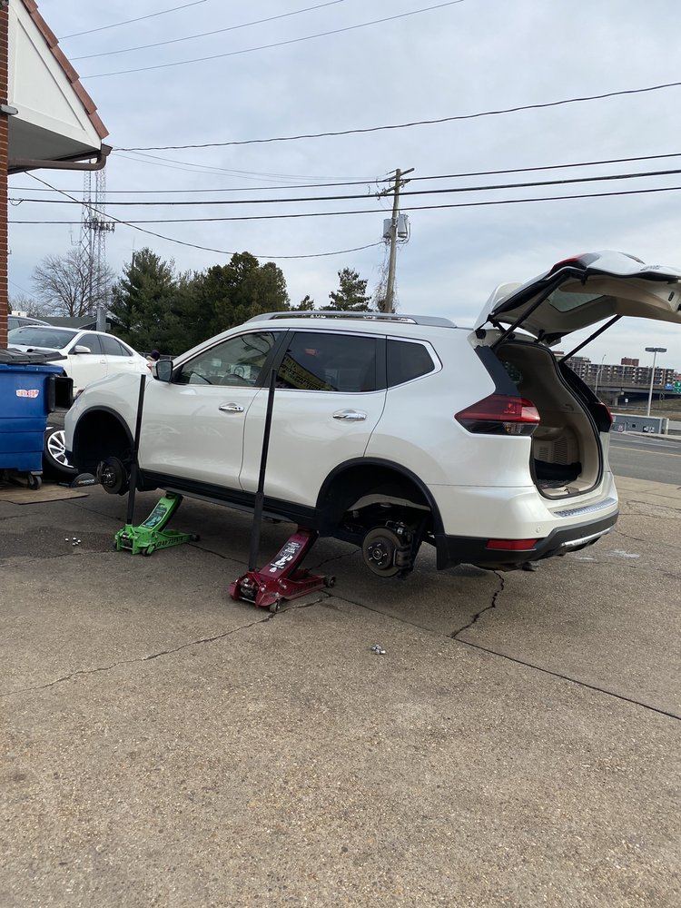 SUV raised on floor jacks with a wheel off for service in the One Stop lot